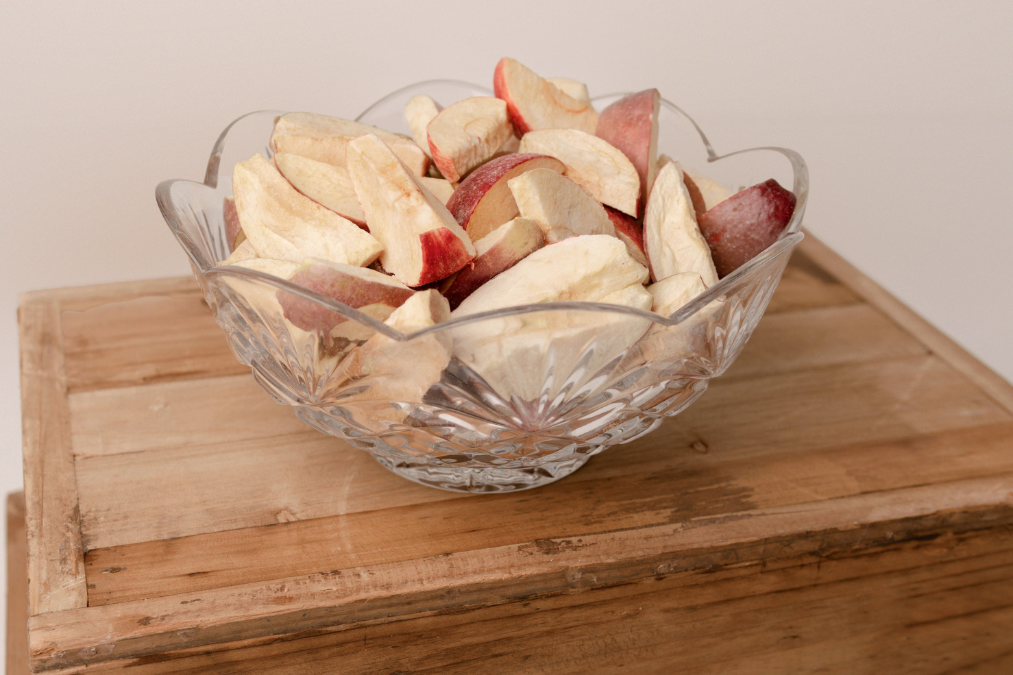 Clear bowl of freeze dried apples on a box.